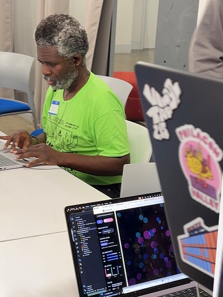 An attendee types code on a laptop that shows glowing colored dots.
