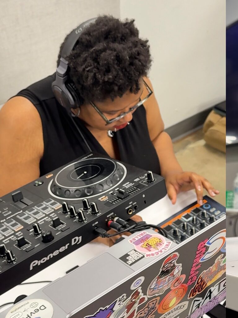 An attendee in headphones works a DJ controller on top of a laptop covered in stickers.