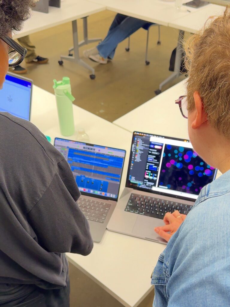 Two laptops side by side: one shows audio tracks, the other shows colored circles from a p5.js sketch.